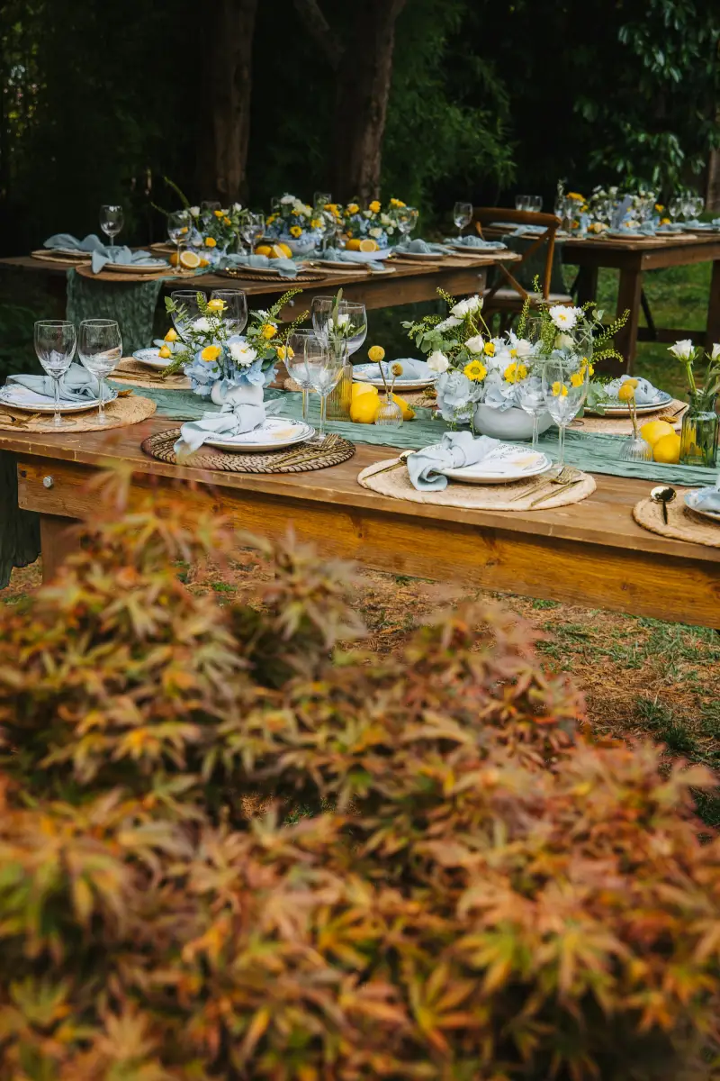 An outdoor reception table set with flowers and place settings for wedding guests